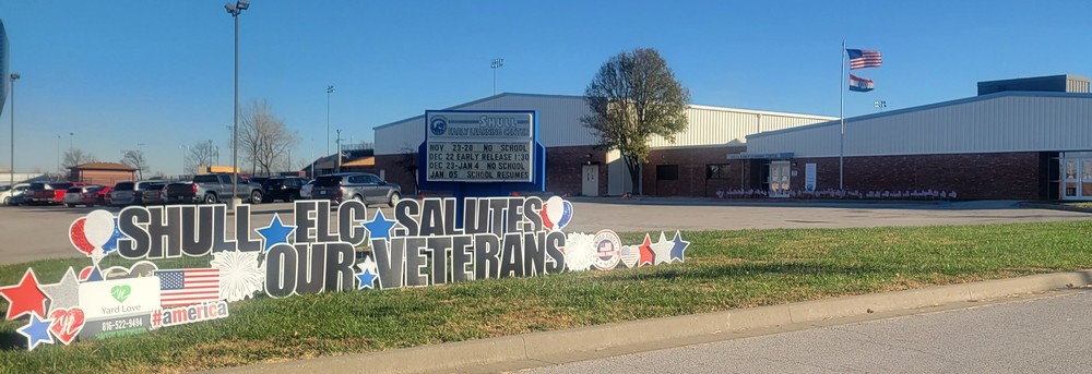 Image of the Shull ELC building with a salute to veterans yard sign and flags